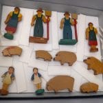 Six wooden farm family figurines and six wooden pig figurines.