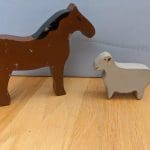 A wooden horse figurine and a wooden sheep figurine.