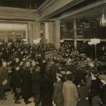 A sepia-toned photograph of a packed delivery room, semi-aerial shot of librarians working diligently.