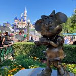 Bronze Minnie Mouse statue with the magic castle in the background.