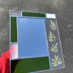 Stained glass picture frame with green, clear, and white glass and pressed yellow flowers.