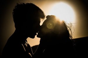 Two people kissing, in the shadow of the sun