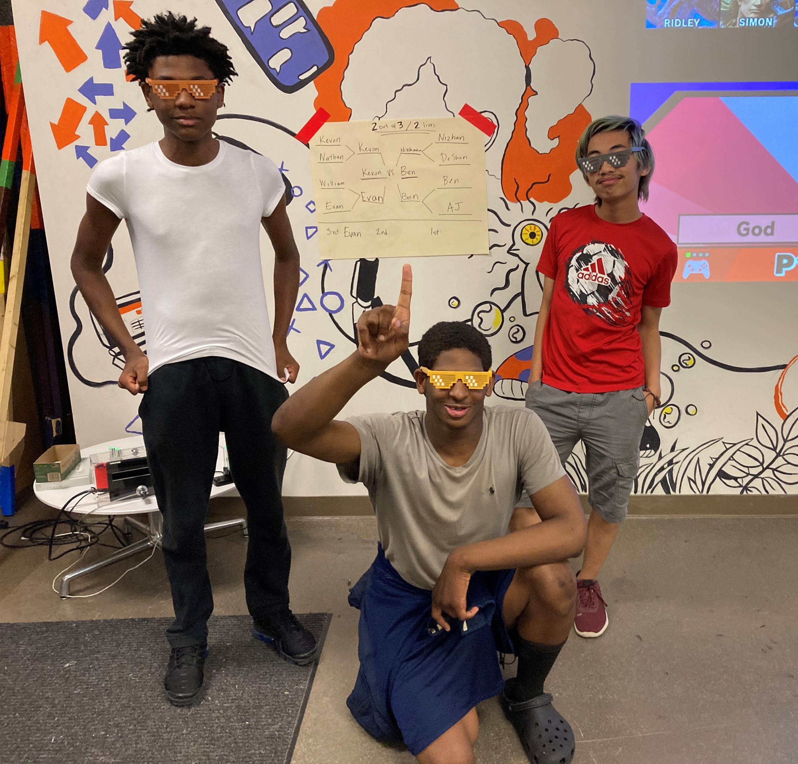 Three teens pose for the camera in celebratory stances. All teens are wearing 3D printed "Deal With It" glasses that they won.