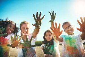 A group of kids having fun with colored power under a clear blue summer sky.