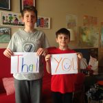 two young boys hold up thank you card