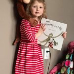 girl holding monkey and me book with monkey toy