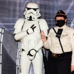 A Stormstrooper and assistant from the 501 Legion pose in front of a Star Wars backdrop