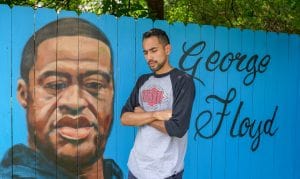 Image is of Xavier Martinez standing with his mural of George Floyd photo by Jeff Burkhead