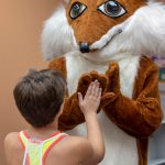 Library mascot Booker high fives a child