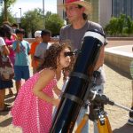 girl looks into large telescope