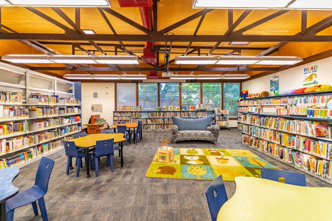 <p>Woodland Library children's area, tables, seating, books</p>