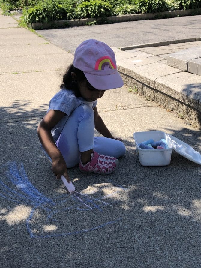 Girl playing with sidewalk chalk.