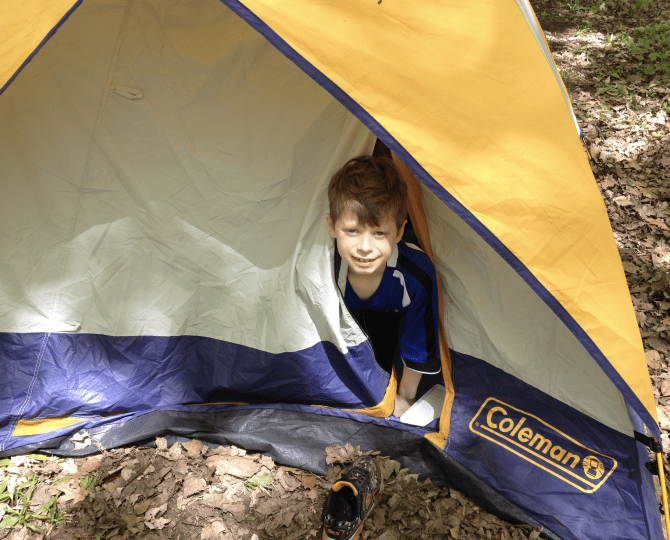 Boy sticking head out of a camping tent.
