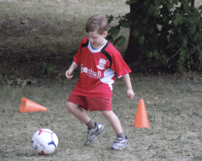 Kid kicking a soccer ball.
