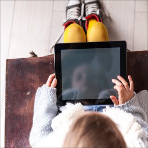 Girl using a tablet on the couch seen from above, Hoopla Kids