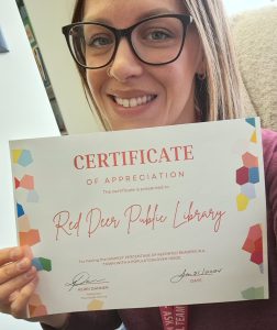 Library staff member holding certificate for the Read for 15 challenge.
