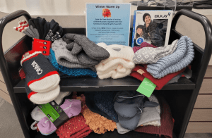 Mitts, toques, socks, and other warm winter wear collected on a library book cart