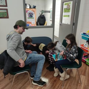 Three children and one adult reading to Katja, RDPL's facility service dog
