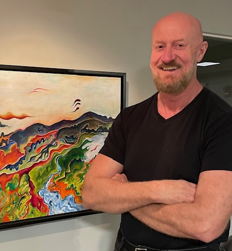 Paul Harris with arms crossed beside a painting.